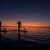 A couple standup paddles through a sunset on the pamlico Sound A couple standup paddles through a sunset on the pamlico Sound