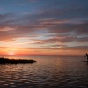 a standup paddleboarder paddles twords a sunset in cape hatteras nc a standup paddleboarder paddles twords a sunset in cape hatteras nc
