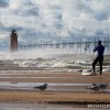 a sufer prepairs for a paddle in lake michigan by the south haven lighthouse