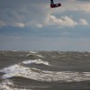 a kiteboarder jumps high over lake michigan on a stormy day