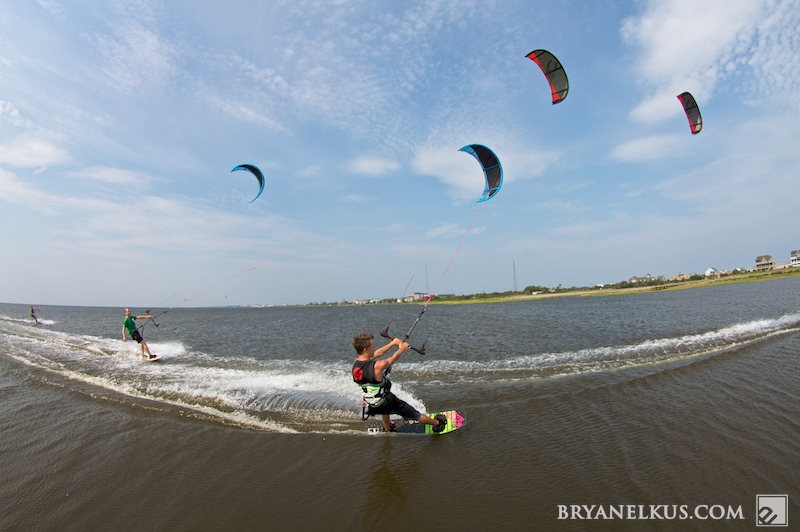 a family of kiteboarders, riding in cape hatteras with their kites in the air