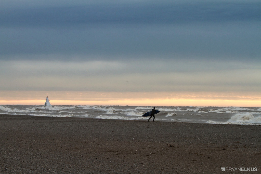 a surfer walks on the beach in Erieau Canada during a stormy day on Lake Erie
